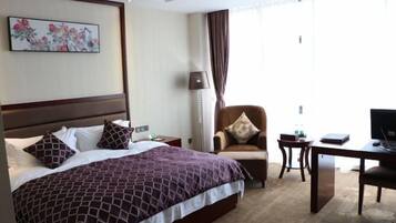 Una habitación de hotel con una cama grande, un escritorio, una silla y un televisor.