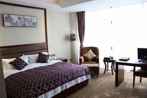 Una habitación de hotel con una cama grande, un escritorio, una silla y un televisor.