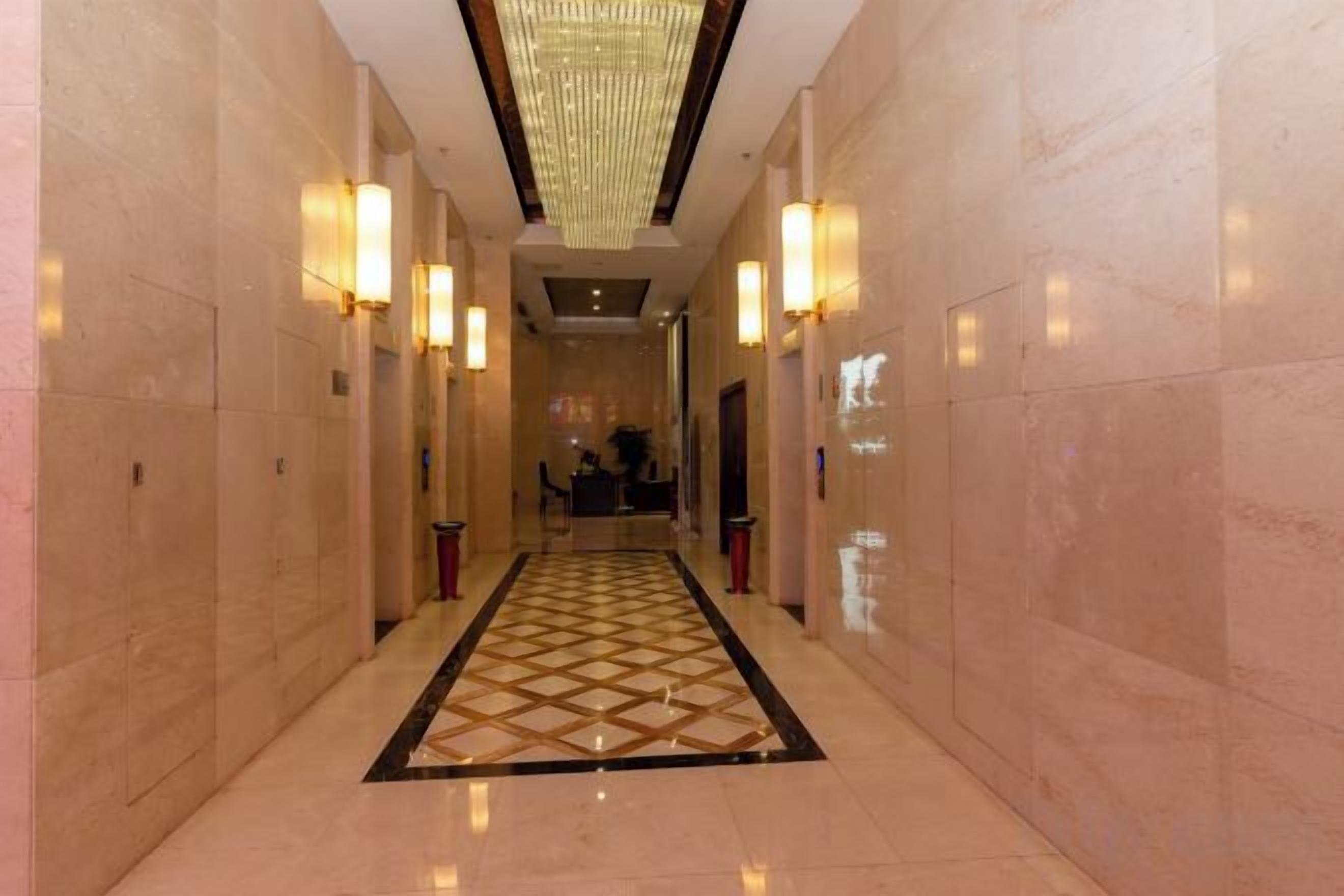 Un pasillo con alfombra estampada, apliques de pared y un candelabro.