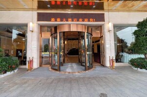 Entrada de hotel con puerta giratoria, puertas de vidrio y un cartel arriba.