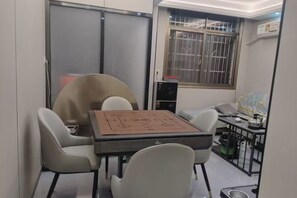 A compact room with a table and chairs, a window with bars, and a bed with a patterned bedspread. - Xiangyuan Hot Spring Hotel (Rucheng)