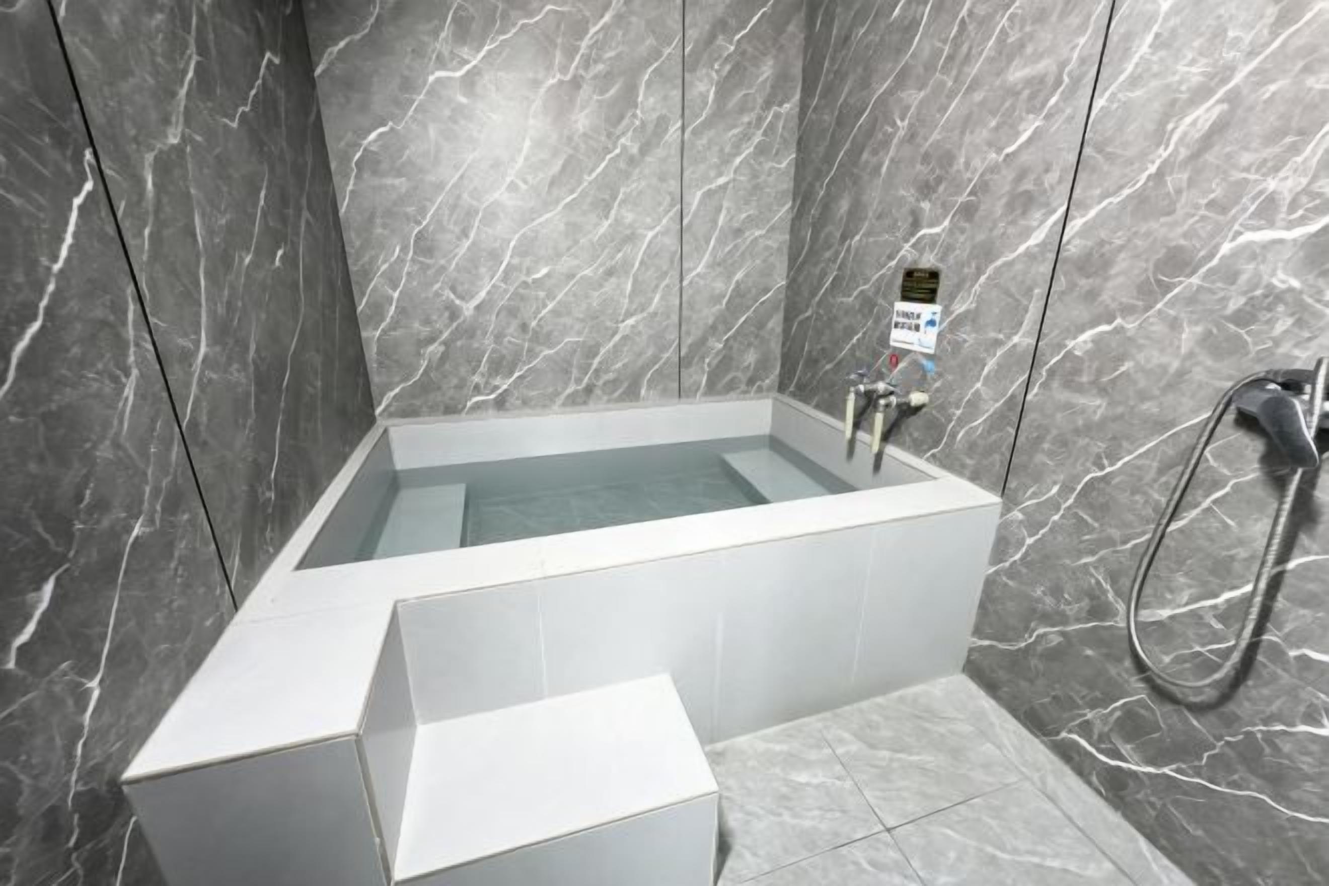 A modern bathroom with a freestanding bathtub, a handheld showerhead, and a control panel.