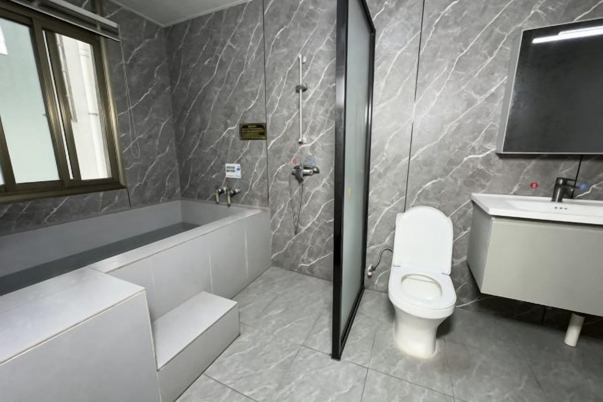 A modern bathroom with a bathtub, toilet, and sink.