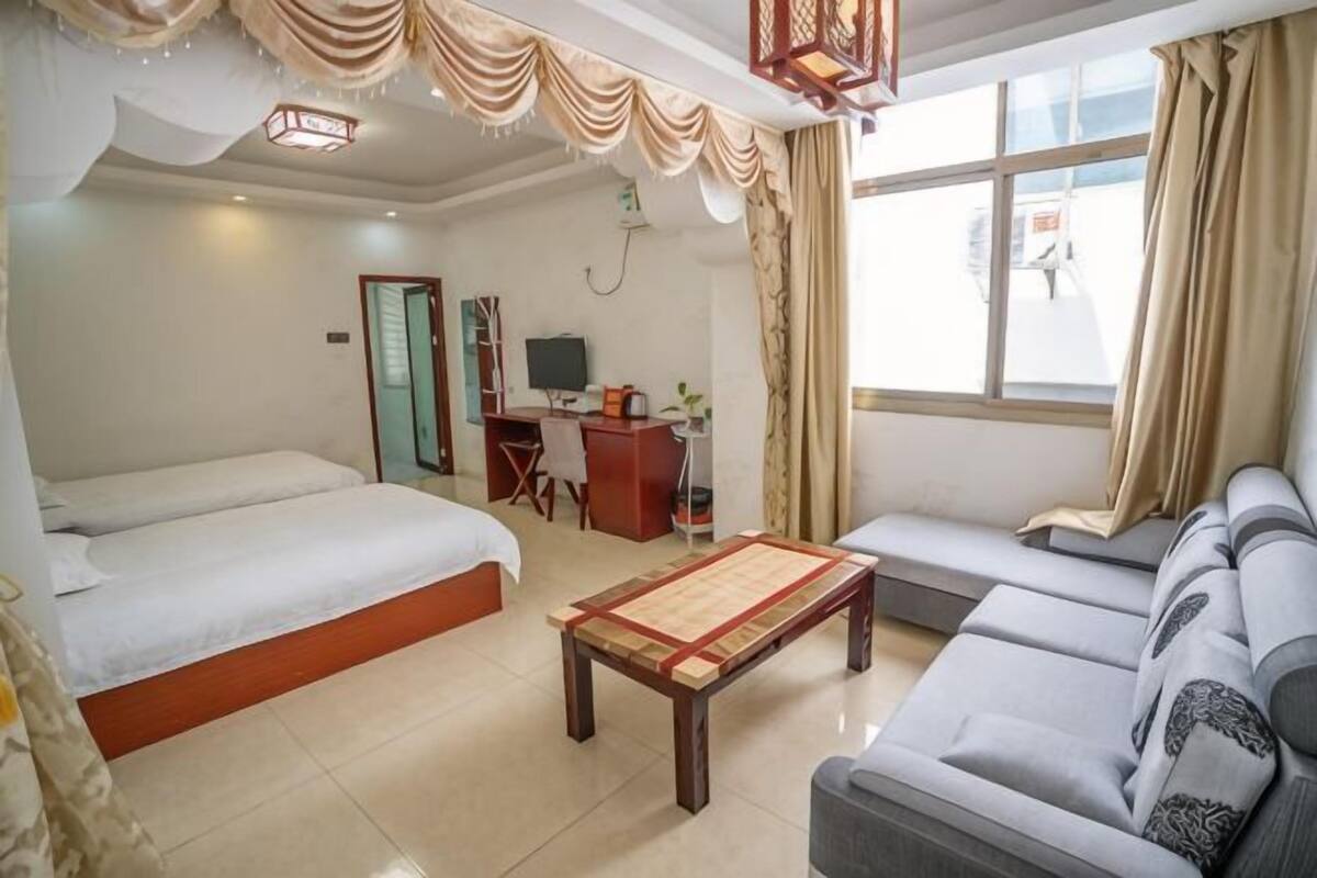 Habitación de hotel con dos camas, un sofá, un escritorio con computadora y una ventana con cortinas.