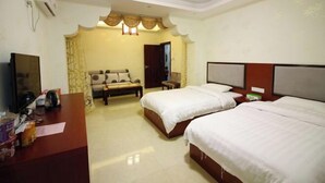 Quarto de hotel com duas camas, uma escrivaninha, uma televisão e uma mesinha.
