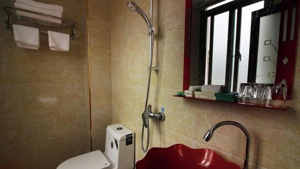 A bathroom with a white toilet, a red sink, and a shower. - Xiangyuan Hot Spring Hotel (Rucheng)