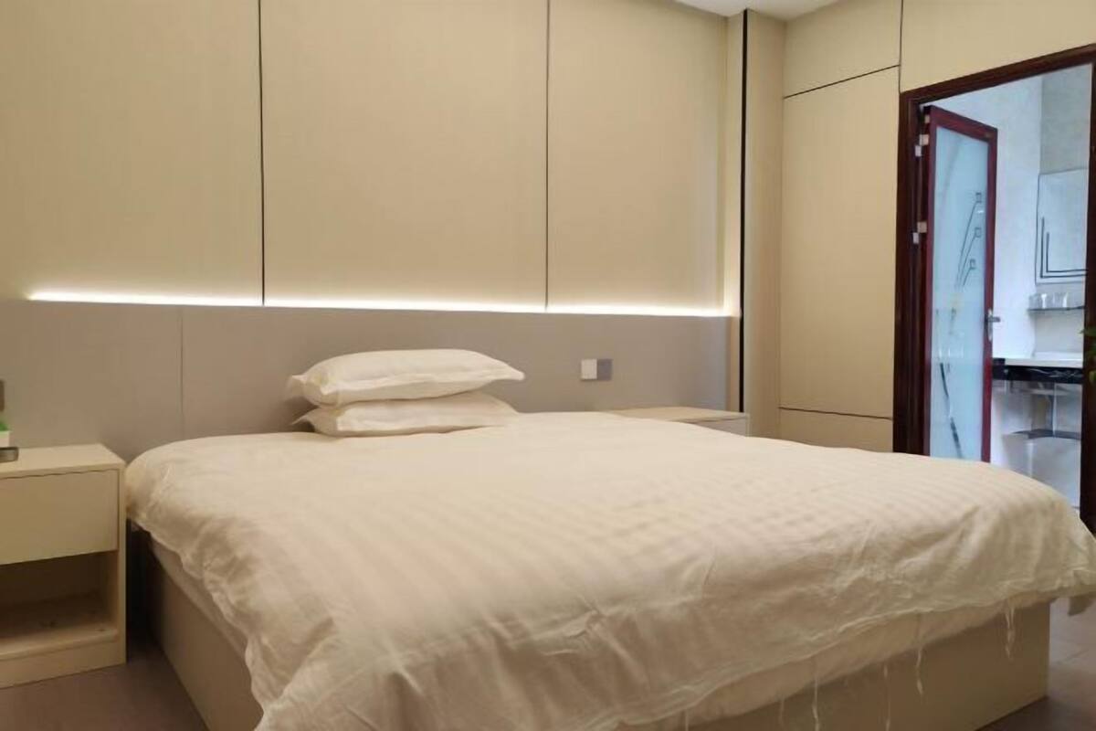 Un dormitorio moderno con cama, mesitas de noche y un armario.