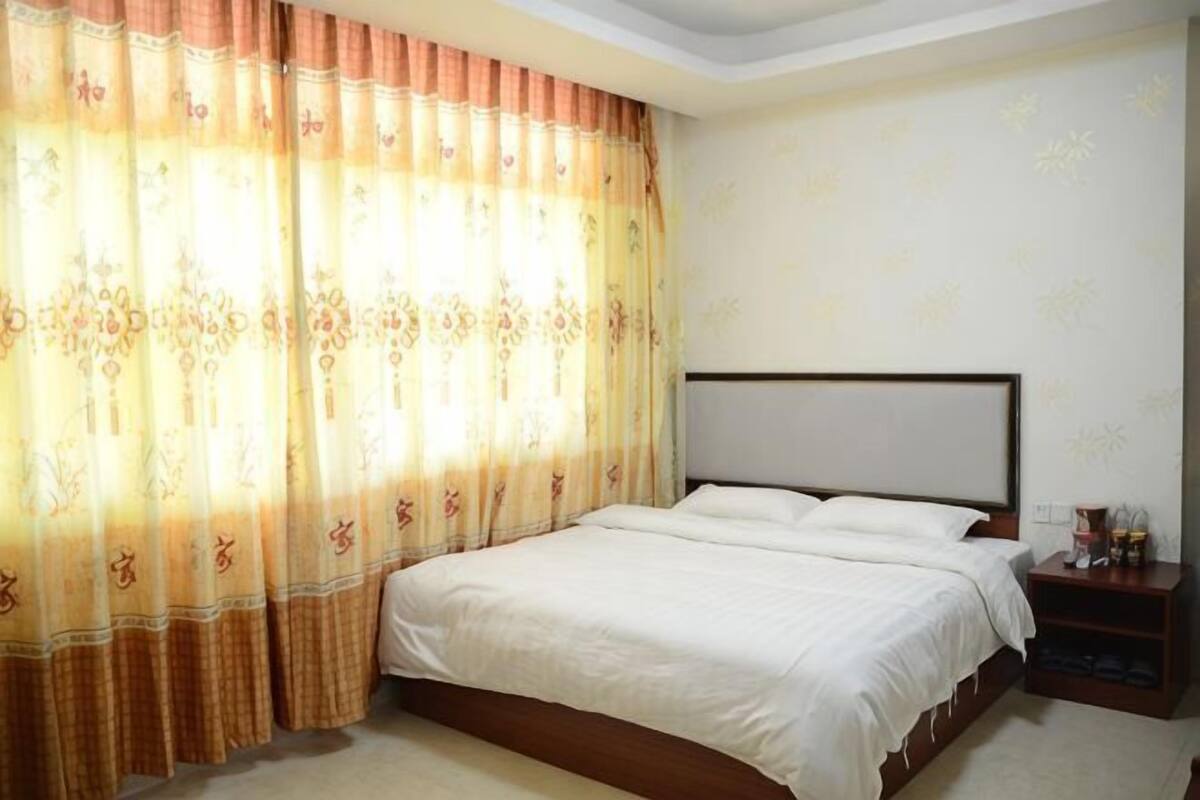 Un dormitorio con cama, cortinas, una mesita de noche y una pared con diseño.