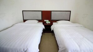 A hotel room with two single beds, a wooden headboard, and a small table between the beds. - Xiangyuan Hot Spring Hotel (Rucheng)