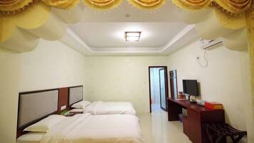 A hotel room with two beds, a desk, and a television.