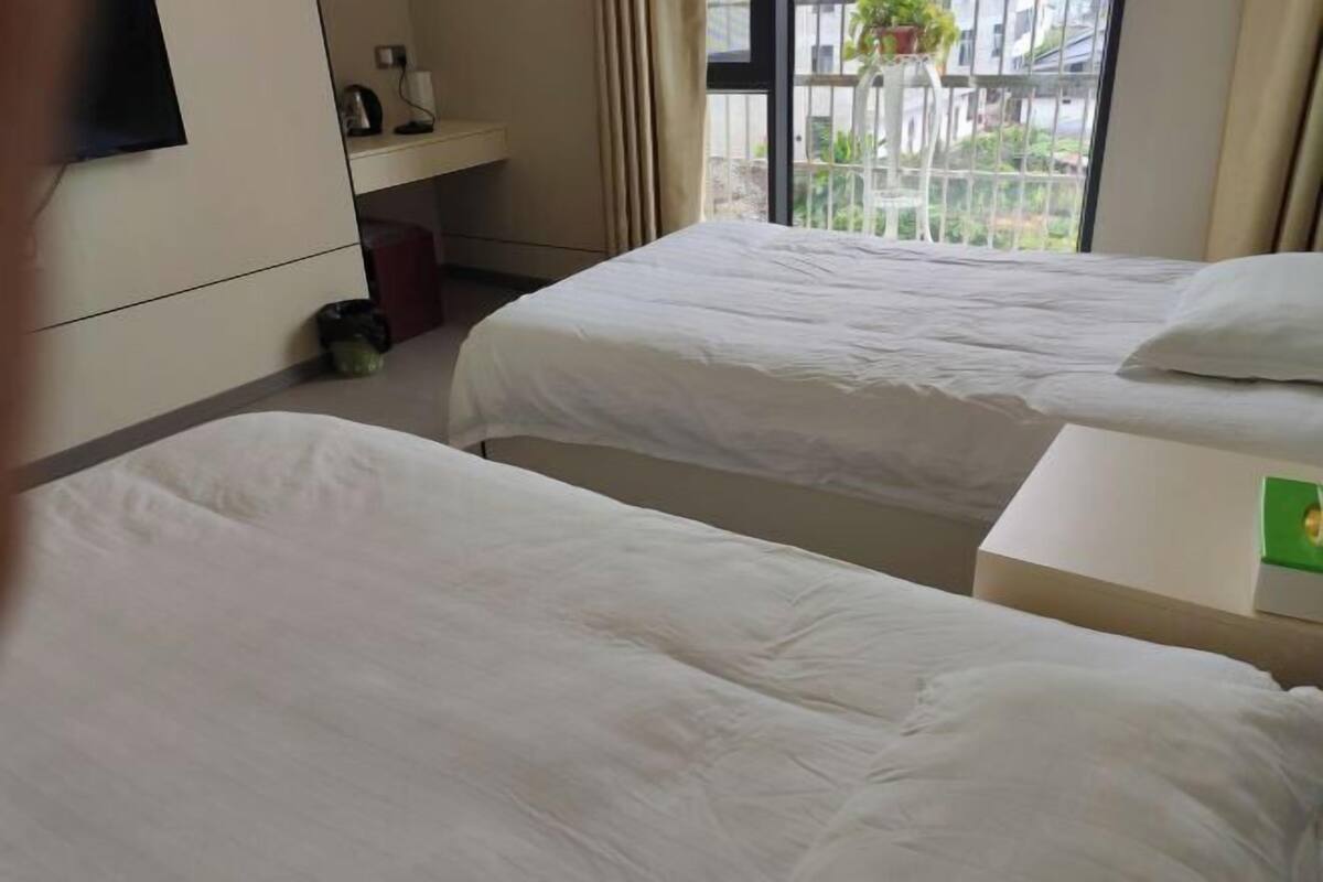 Habitación de hotel con dos camas, un escritorio pequeño, televisor y ventana con vistas al exterior.