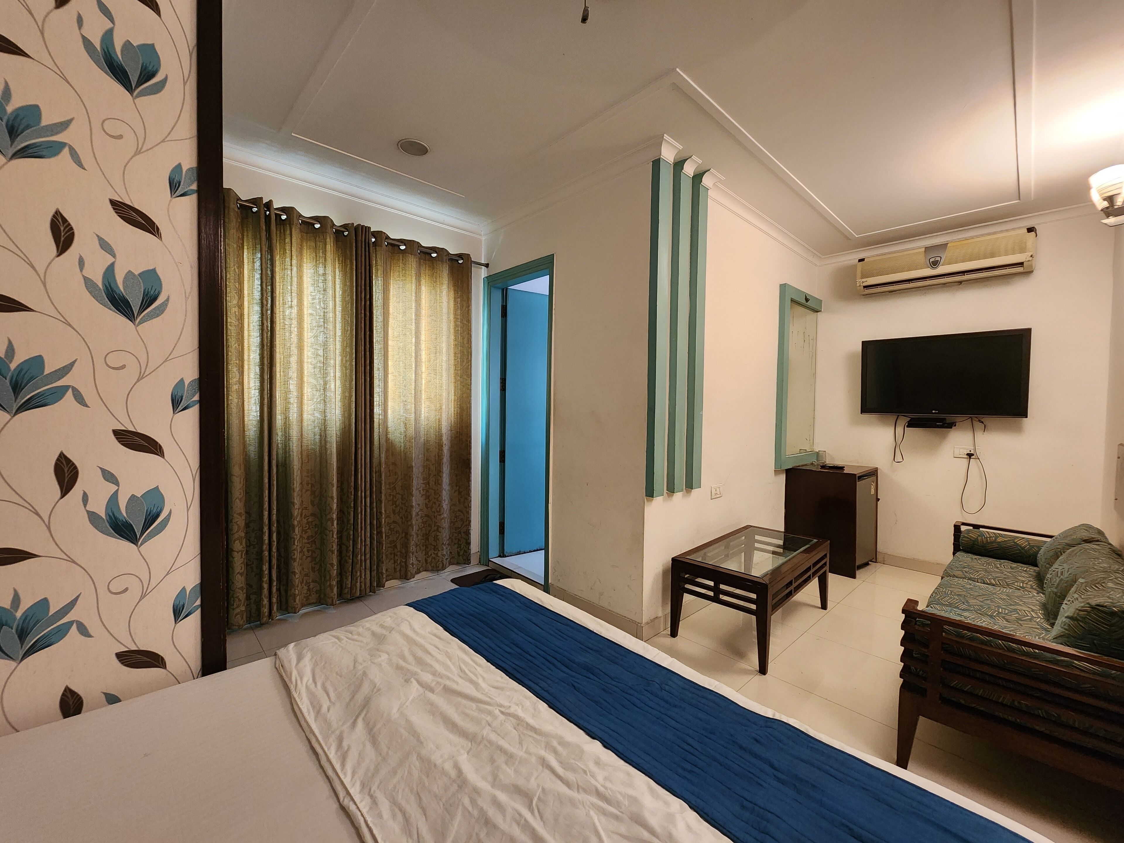 A hotel room with a bed, a TV, a desk, and a chair.