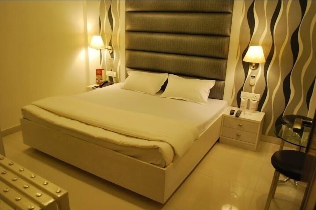 A neatly made bed with a headboard, bedside tables with lamps, and a chair.