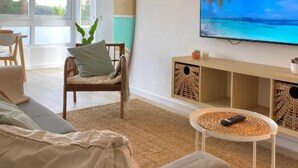 Un salon avec un canapé, un fauteuil, un téléviseur et une planche de surf.