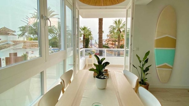 Un espace repas moderne, doté d’une grande table, de chaises et offrant une vue sur l’extérieur.