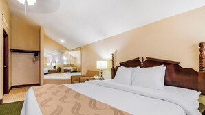 A hotel room with a large bed, a mirror, a bedside table, and a bathroom visible through the mirror.