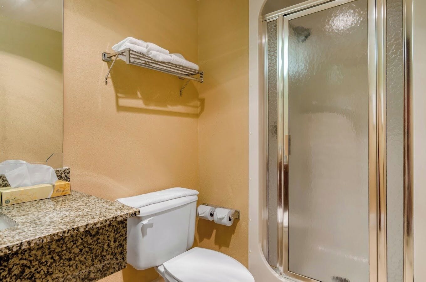 A bathroom with a toilet, a sink, a towel rack, and a shower stall.