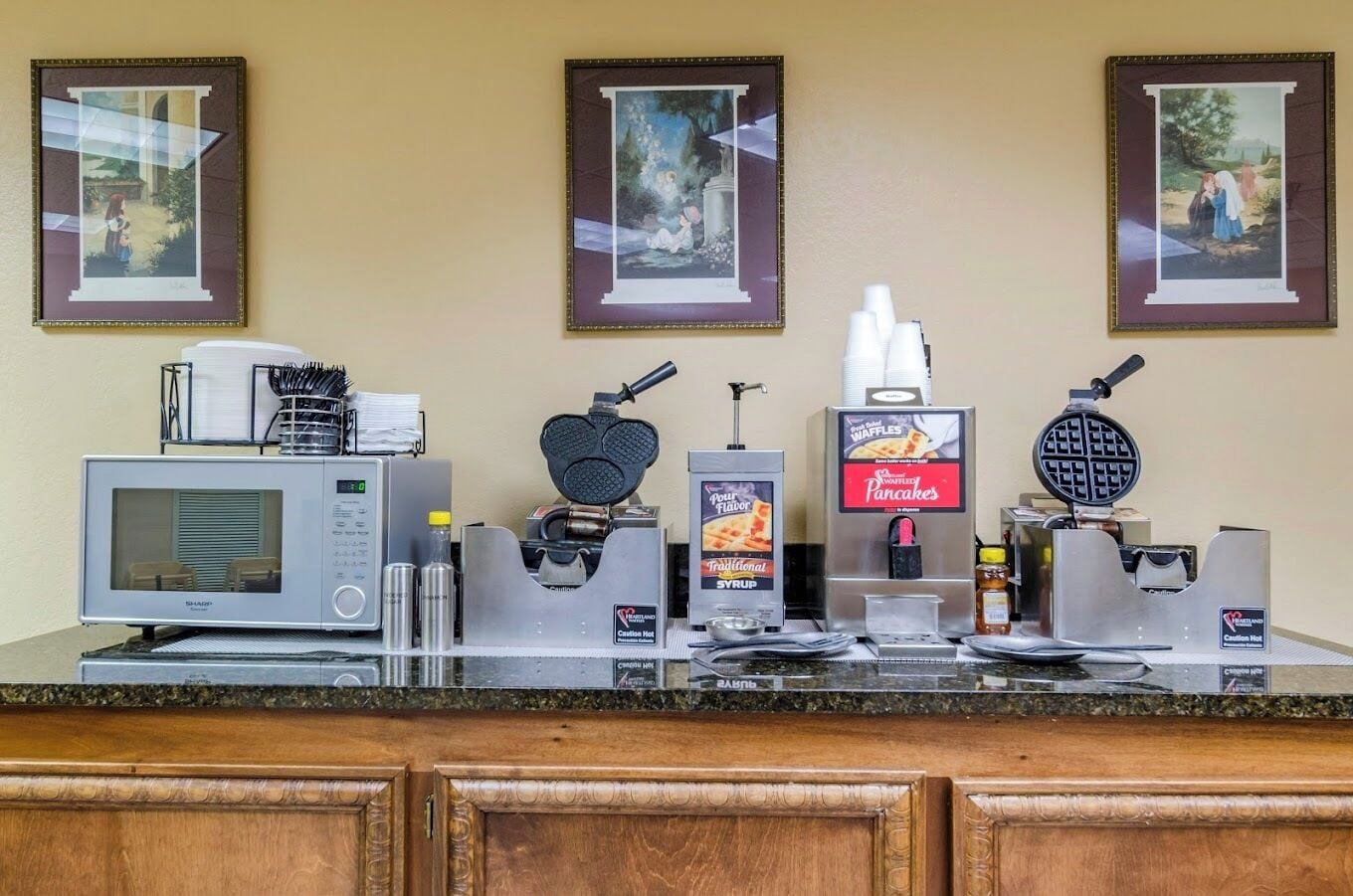 Un plan de travail de cuisine équipé d’un four à micro-ondes, d’un appareil à gaufres, d’un distributeur de sirop et d’un gaufrier.