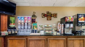 A coffee shop counter with various coffee machines, a bowl of fruit, and a sign that reads "Coffee".