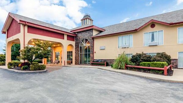 A hotel with a central entrance, a stone facade, and a red roof.