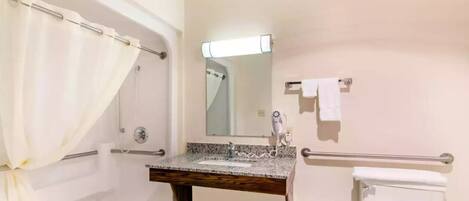 Ein Badezimmer mit Dusche, Waschbecken mit Spiegel, Handtuchhalter und Toilette.