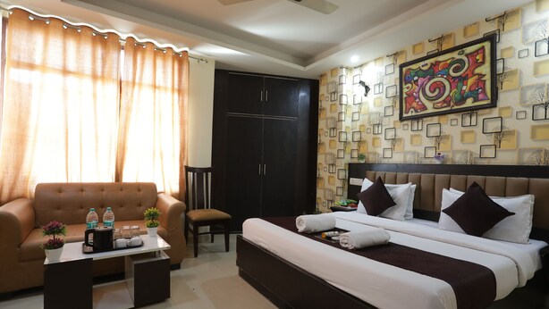 A hotel room with a bed, sofa, coffee table, and a wall with a decorative pattern. - HOTEL LUXURY GLOBAL STAY (New Delhi)