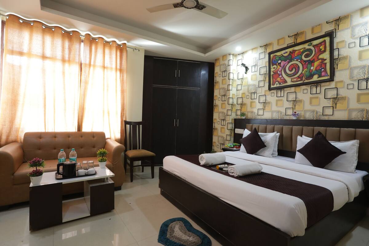 A hotel room with a bed, sofa, coffee table, and a wall with a decorative pattern.