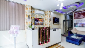 A hotel reception area with a sign indicating rooms are available, a reception desk, a television, and a signboard listing services like hotel rooms, money exchange, and airport transfer. - HOTEL LUXURY GLOBAL STAY (New Delhi)