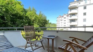 Un balcon avec un banc en bois, deux chaises pliantes et une petite table.