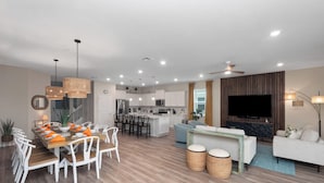 A modern living room with a TV, sofa, and dining area.