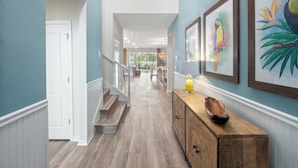 A hallway with wooden flooring, a staircase, and a wooden console table with a decorative bowl.