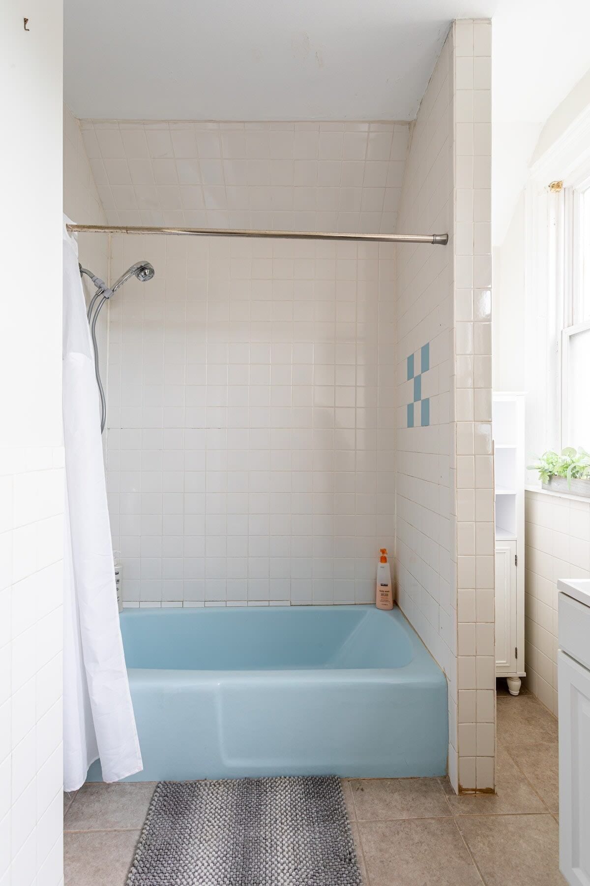 A bathroom with a bathtub, a shower, and a white tiled wall.