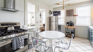 Una cucina moderna con elettrodomestici in acciaio inossidabile, un tavolo da pranzo bianco e sedie trasparenti.