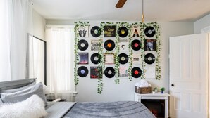 Una camera da letto con un letto, una collezione di dischi fissata al muro e una porta bianca.