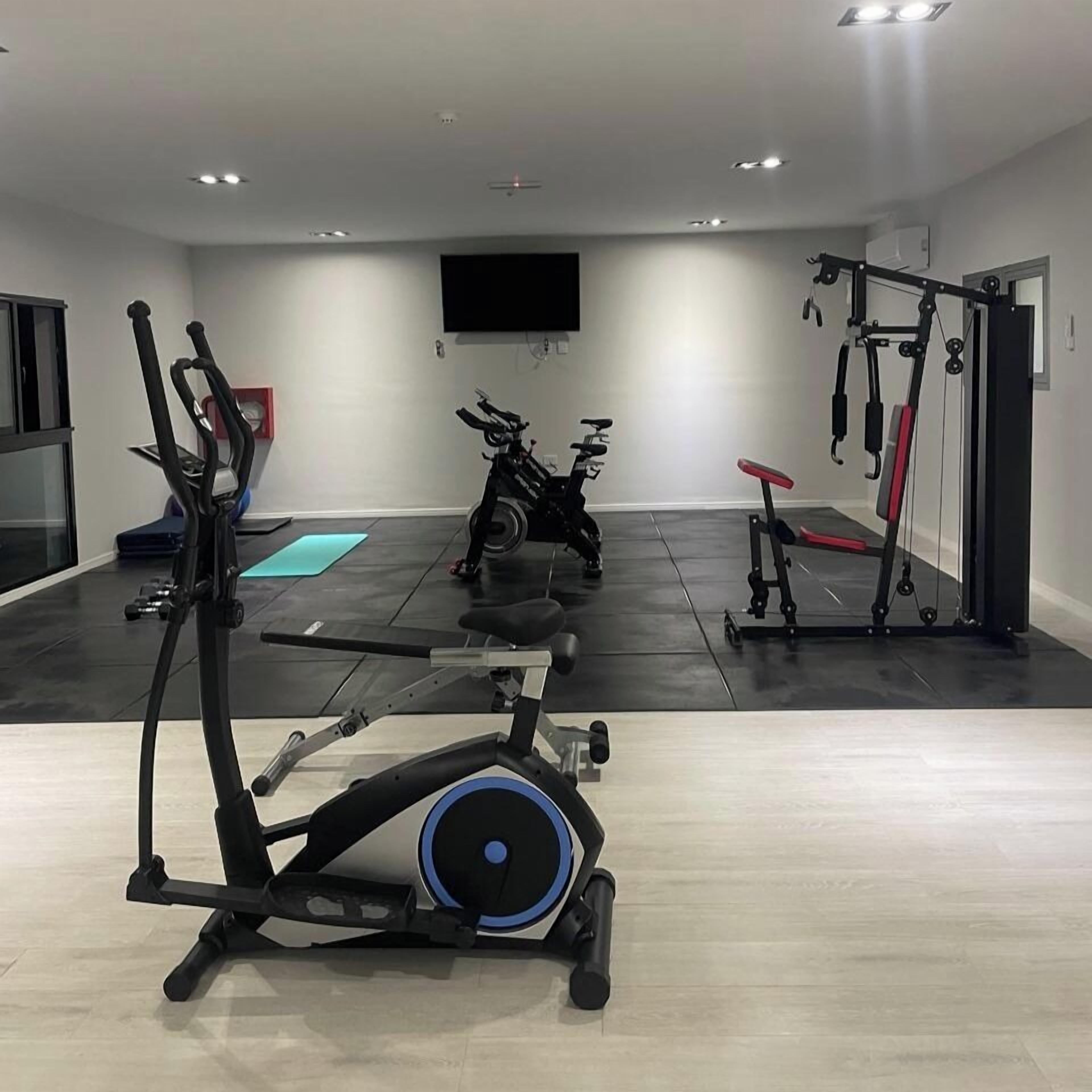 Ein Fitnessraum mit Trainingsgeräten, einem Fernseher und einem großen Fenster.