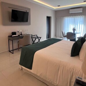 Une chambre d’hôtel comprenant un lit, un bureau avec une chaise, un téléviseur fixé au mur et un appareil de climatisation.