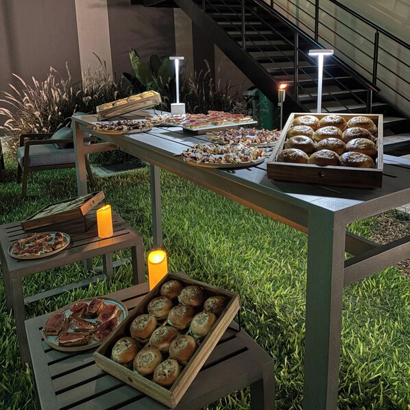 A buffet table with various food items, candles, and a staircase in the background. - Hotel Boutique Gualamba (General Pinedo)
