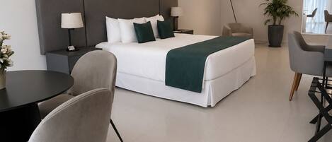 A modern hotel room with a bed, bedside tables, a desk, and a chair.