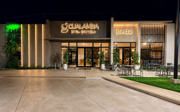 L’entrée d’un hôtel au design moderne, avec une enseigne bien visible indiquant « GUALAMBA HOTEL BOUTIQUE » et une section distincte portant l’inscription « Restó ».