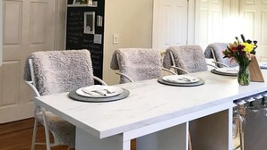 A dining area with a white table, four chairs, and three pendant lights. - Renovated 2BR Retreat / Modern Comforts Included (Bridgeport)