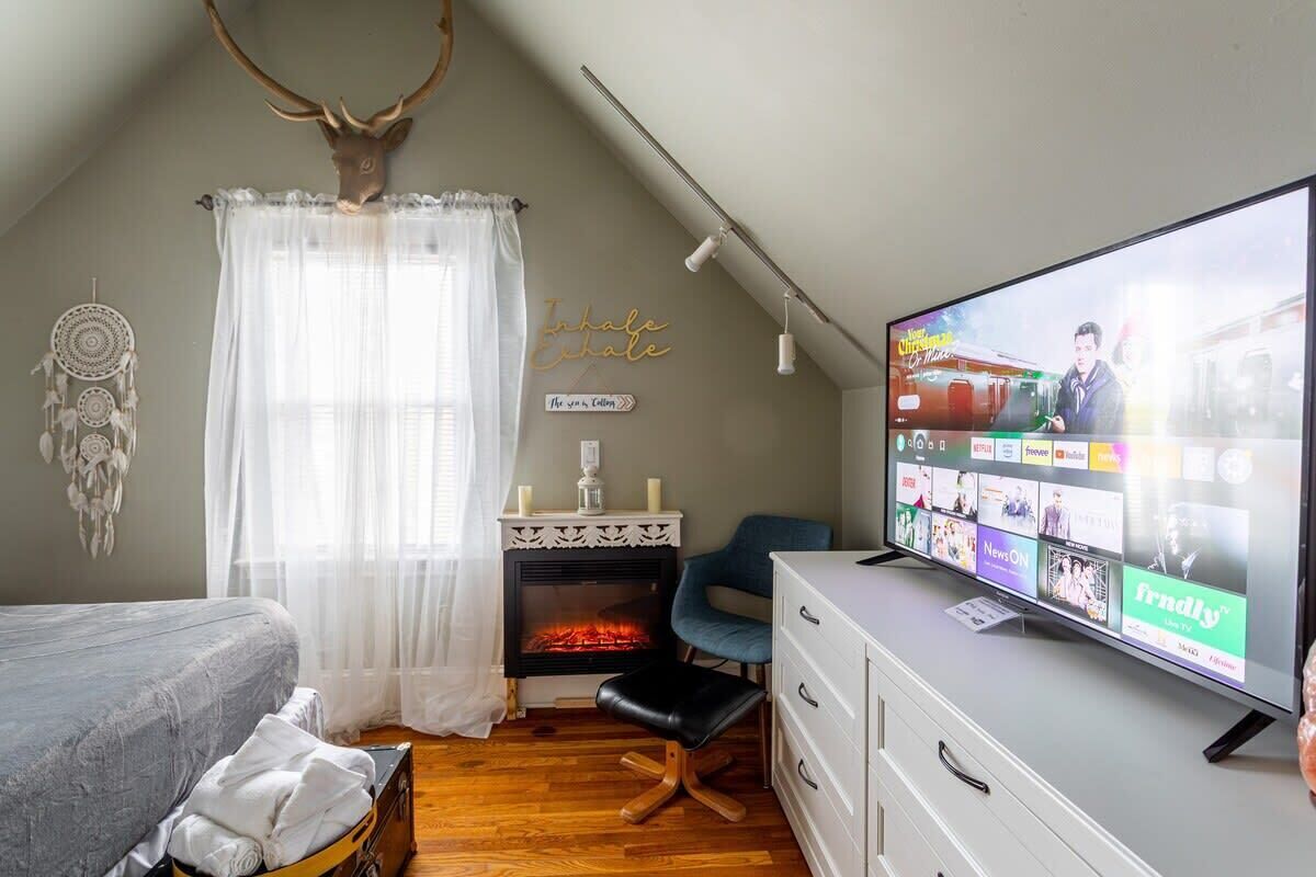 Een gezellige kamer met een open haard, een televisie waarop een nieuwskanal staat en een droomvanger aan de muur.