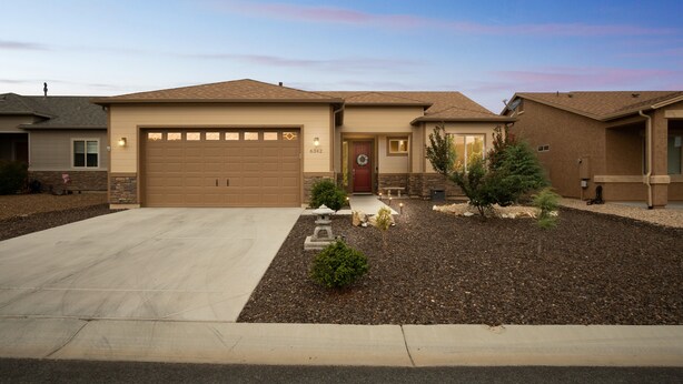 A residential house with a garage, a front yard with landscaping, and a stone pillar. - Cozy Granville Retreat W/ Modern Amenities 3 Bedroom Home (Prescott Valley)