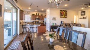 A modern kitchen with a central island, bar stools, and a dining table with a vase of flowers. - Cozy Granville Retreat W/ Modern Amenities 3 Bedroom Home (Prescott Valley)
