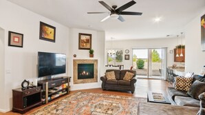 A spacious living room with a flat-screen TV, a fireplace, a ceiling fan, and a large rug. - Cozy Granville Retreat W/ Modern Amenities 3 Bedroom Home (Prescott Valley)