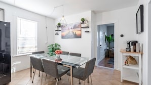 Una cocina moderna con una mesa de comedor de vidrio, sillas grises y una lámpara colgante.