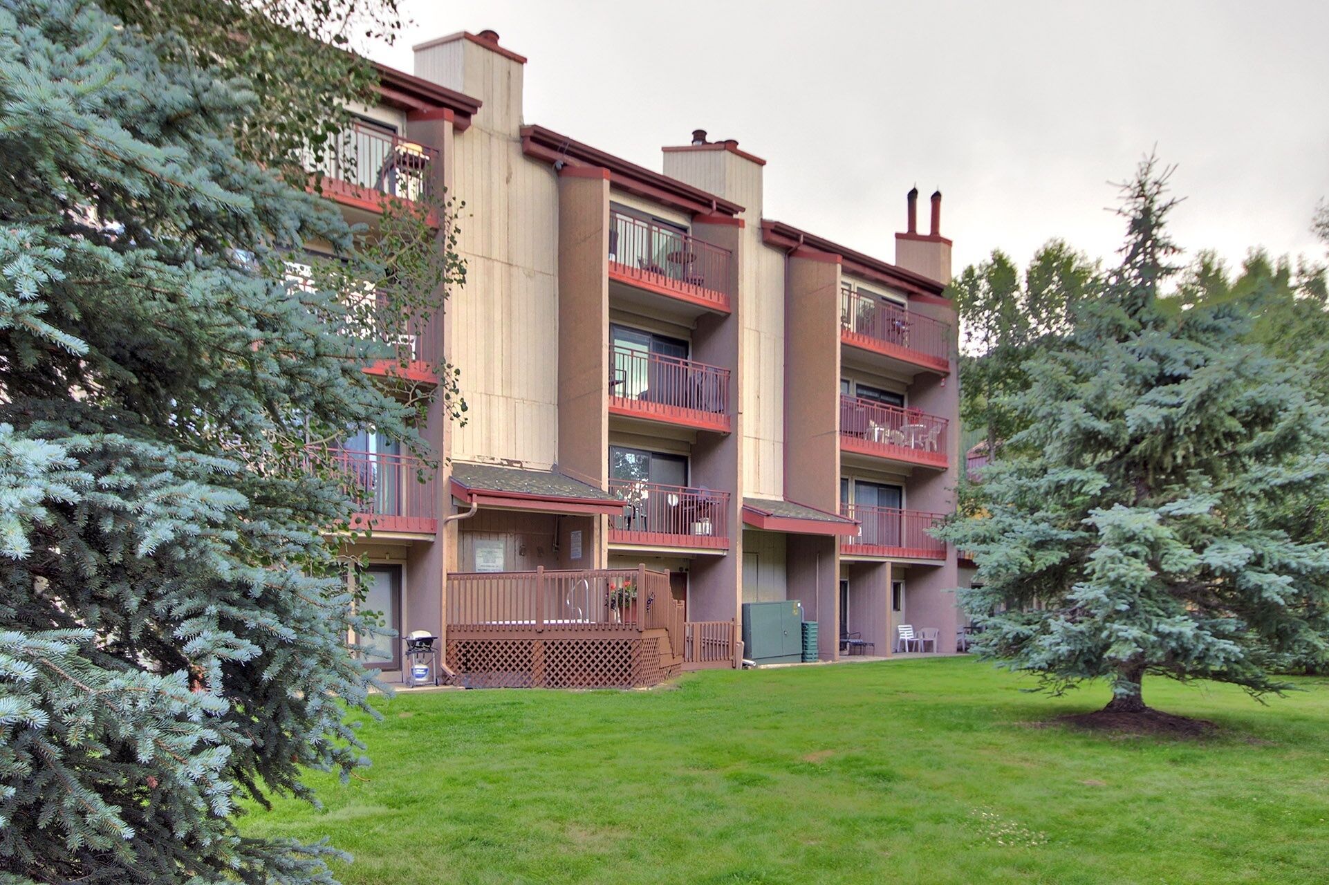 Un immeuble à plusieurs étages doté de balcons, d’une courClose et d’arbres à feuilles persistantes.