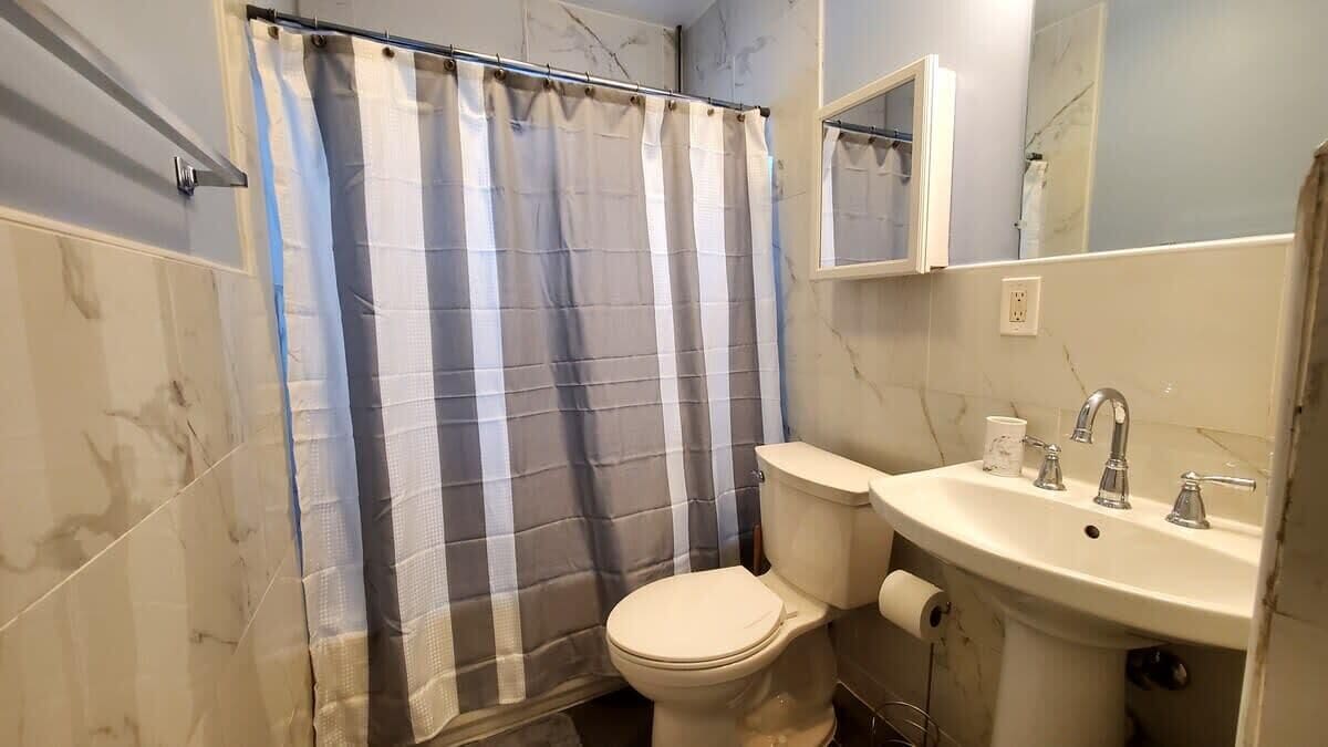 Une salle de bain avec des toilettes, un lavabo et un rideau de douche.