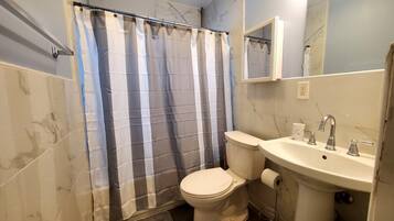 Une salle de bain avec des toilettes, un lavabo et un rideau de douche.
