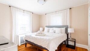 Un dormitorio ordenado con cama, mesitas de noche y un escritorio.