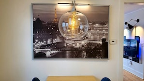 A framed cityscape photograph with a glass sphere in the center, mounted on a wall above a wooden table. - The Blue Sapphire: Modern & Stylish 2BR w/ 2 King Beds & Full Kitchen (Bridgeport)